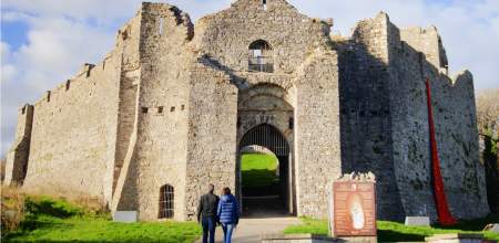 Two people walking into Oystermouth Castle.
