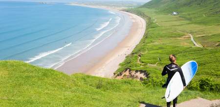 Surfer walking down to Rhossili Bay Beach