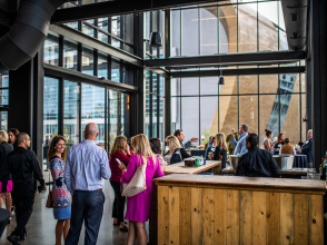 Group of meeting attendees mingling at Gather with Fiserv Forum out the window