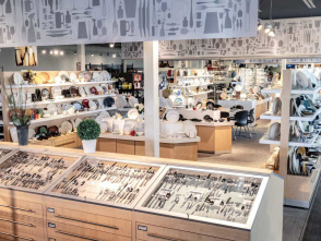 Bright retail showroom featuring organized displays of silverware, dinnerware, and kitchen accessories, with shelves stocked with plates, bowls, and serving pieces.