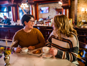 Two women smiling and drinking coffee in a cafe