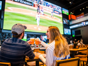couple cheersing beer at bar with baseball on tv