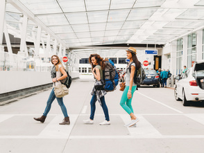 three women smiling after getting baggage and walking out of airport