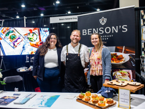woman, man, and another woman smiling at a booth displaying lobster rolls and smores pie