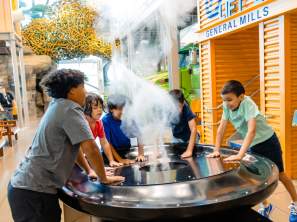 Kids experiment with a cloud making machine at Amazeum