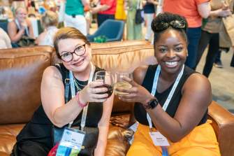 A white woman and a Black woman cheers wine glasses during a reception for a conference in Madison. Wisconsin