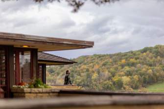 A woman looks out onto the rolling hills of Spring Green from the balcony at Taliesin