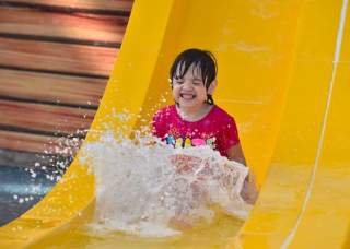 Girl sliding down waterslide and splashing into water