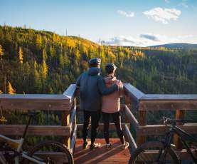 Couple taking in the view at Myra Canyon Trestles during Golden Larch Season 1