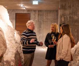 Group Listening to a Guide while Holding Wine Glasses Inside the Wine Cave at 50th Parallel