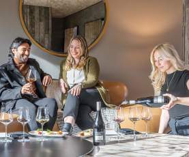 A woman pouring wine into a glass for a couple.