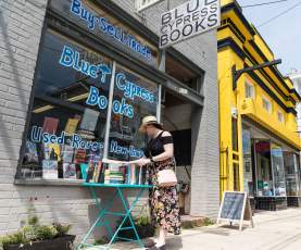 a woman browses the selection of books outside of Blue Cypress Books on Oak Street