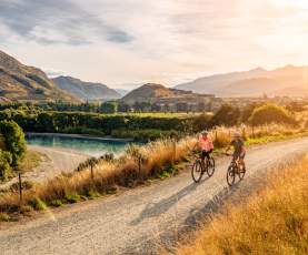 A couple cycle the Twin Rivers Trail in the evening summer light