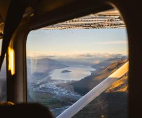 View from a plane window at sunrise looking out rivers, lakes and mountain ranges