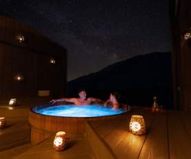 A couple enjoy a private spa at Onsen Hot Pools in Arthurs Point on a clear night