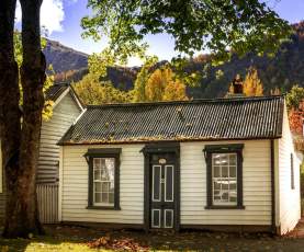 External view of old cottage surrounded by autumn trees