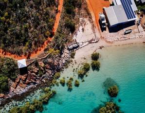 Overhead view of coastline at Cygnet Bay showing the red coloured pindan soil, white sand, turquoise waters as well as the mangroves and rocks