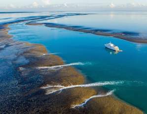 Aerial shot of the True North cruise ship at Montgomery Reef on the Kimberley Coast with the tide starting to recede from the reef