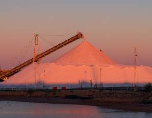 A large pile of salt in Port Hedland is bathed in a pink glow from the sunset.