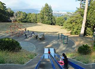 Junipero Serra County Park in San Bruno. Children going down a slide and playing on a playground.