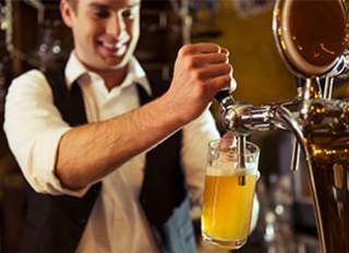 Smiling man pouring beer from tap