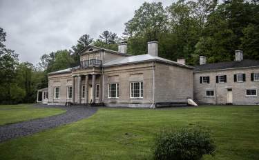 A large stone historical building called Hyde Halle with a pathway and a grassy front lawn.