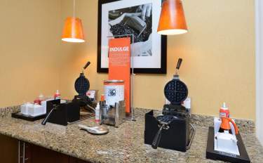 Close-up of a hotel breakfast area with waffle makers, syrup, and toppings ready for guests to create their own waffles in Fayetteville, North Carolina.