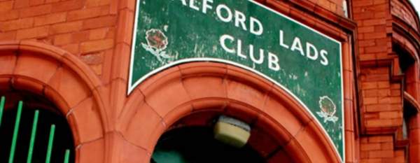Exterior of red brick building with sign saying Salford Lads Club