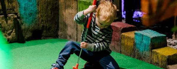 Child playing crazy golf on indoor course