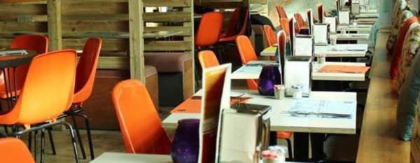 Restaurant set up with cutlery and menus with orange seating