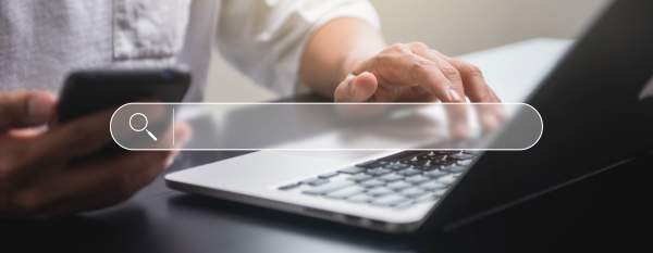 A search box overlayed on top of an image of a person browsing their laptop and phone.