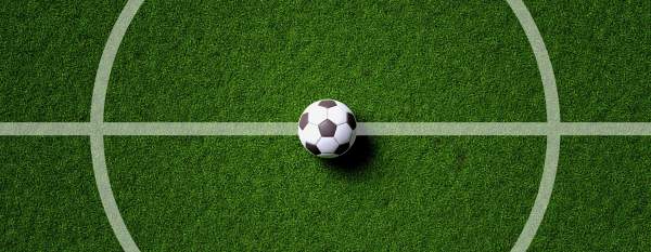 A soccer ball sits at the center circle on a soccer pitch.