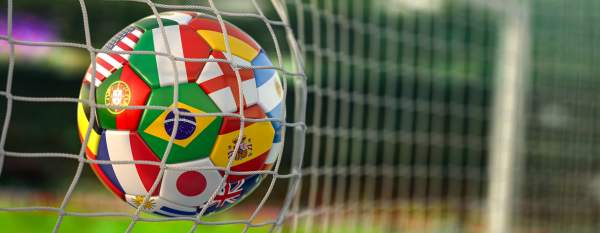 A soccer ball with the flags of countries from around the world, hits the net of a goal.