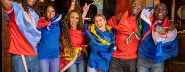 Group of fans draped in international flags celebrating together, symbolizing the global excitement and travel opportunities around the World Cup.