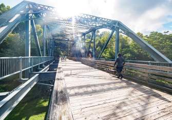 Man Walking Dog Across Bridge