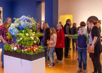 A group of people looking at a flower display in an art museum