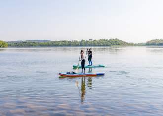 Two people paddleboarding on a lake
