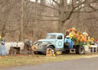 A vintage truck with an Easter bunny and large, fake carrots on the bed of the truck
