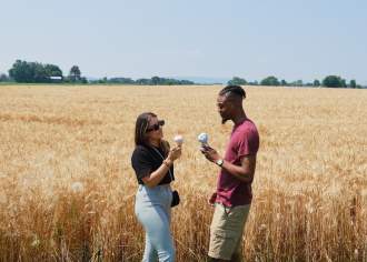 Two people eating ice cream cones in a field with tall grass