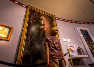 A young boy looking up at a large painting in a museum