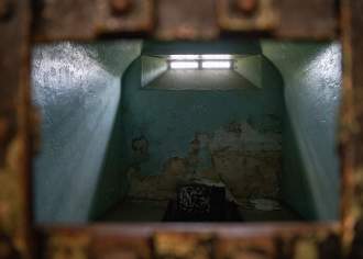 An old, eerie jail cell with a glowing window at the top