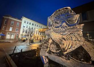 Close up of an ice sculpture shaved into Santa Claus with sunglasses on while on display on a main street