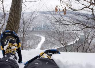 Booted feet in snowshoes overlooking a snow covered overlook