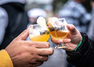 Two people cheersing glasses that read, "Kennett Square Brewfest"