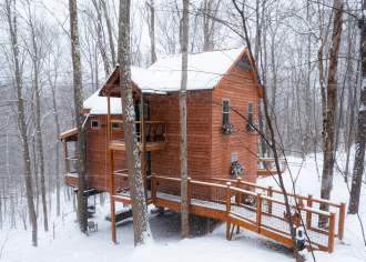 Treehouse cabin in the woods in Ohiopyle State Park covered in snow.