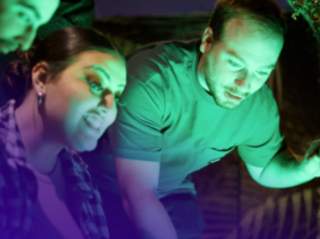 Man and woman looking into green glow