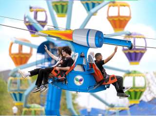 Riders waving with Ferris wheel in background