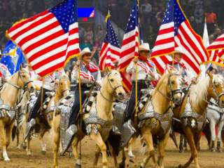 Group of riders on horses holding American flags