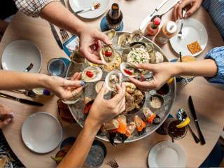 Friends share raw oysters, crab, and other chilled seafood as part of the seafood Plateau at Delacroix