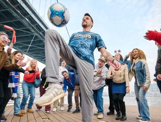 A man playing with a soccer ball with people cheering and standing around him
